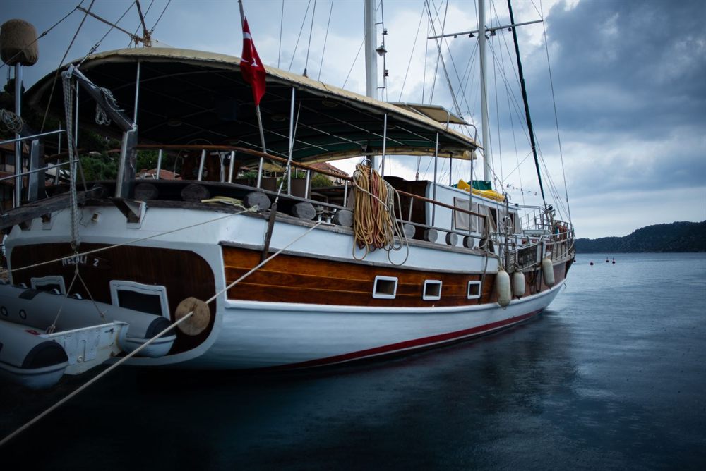 Traditional wooden Turkish gulet moored under a cloudy sky