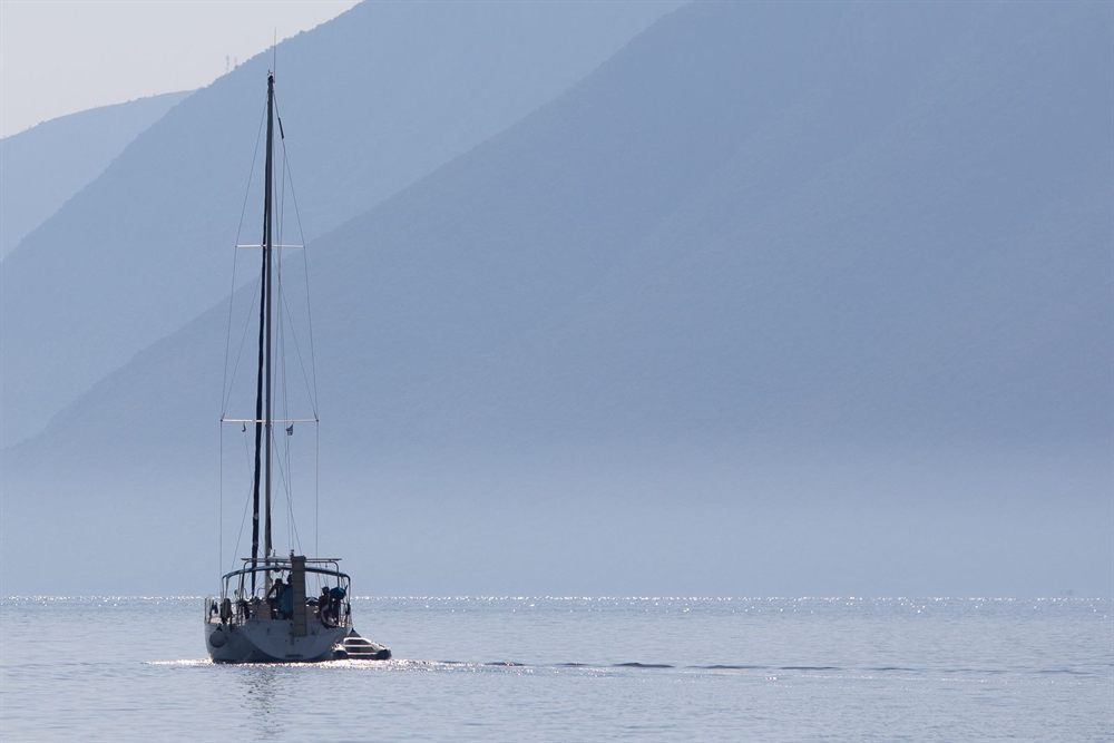 Sailboat on calm water below the misty mountains of Lefkada, Ionian Sea