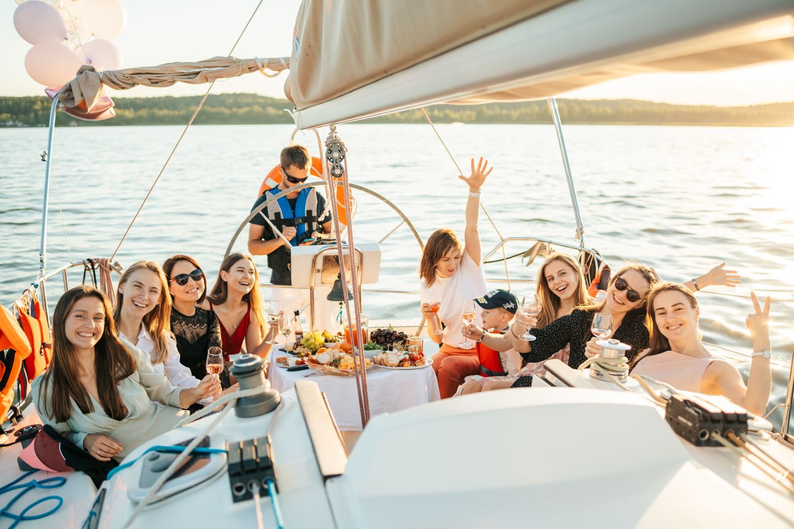 Friends celebrating together on the bow of a sailing yacht at sea, a classic group sailing trip