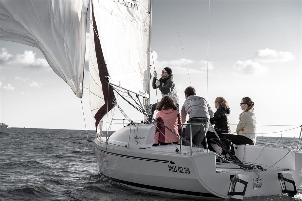 Group of adults sitting in the cockpit of a heeling sailboat under full sail
