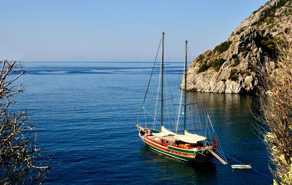 Gulet anchored in a deep blue bay below rocky cliffs near Datca, Turkey